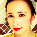 Closeup of Kim-Mai in a yellow top in front of a brick red staircase with a white metal grid railing