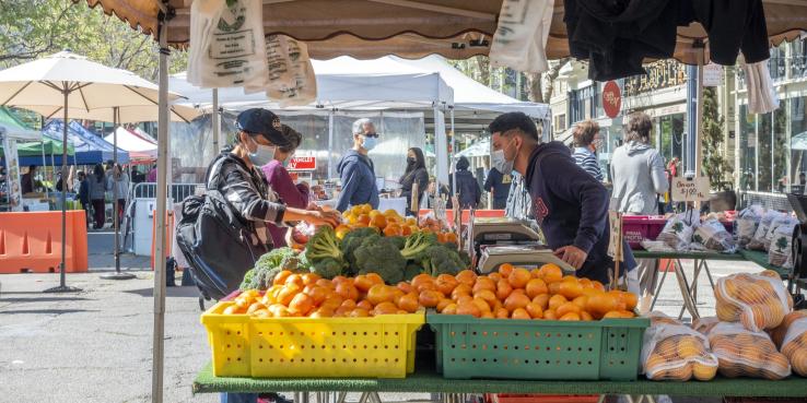 Patrons purchase vegetables at a vegetable stand