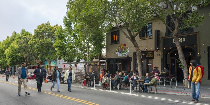 Valencia St, San Francisco - people walking in the streets, relaxing in the outdoor seating area of a restaurant
