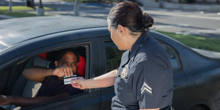 Man giving his drivers license to a police officer.