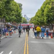 A slow street in San Francisco where pedestrians are walking, biking and scootering.