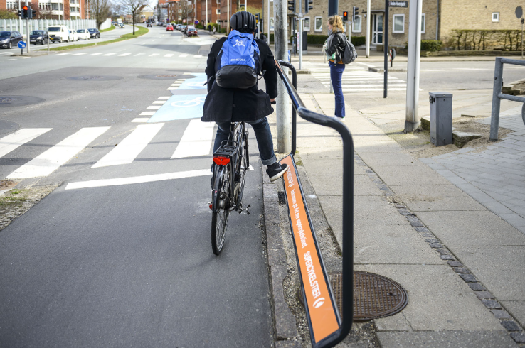 A convenient footrest helps a cyclist waiting at an intersection.