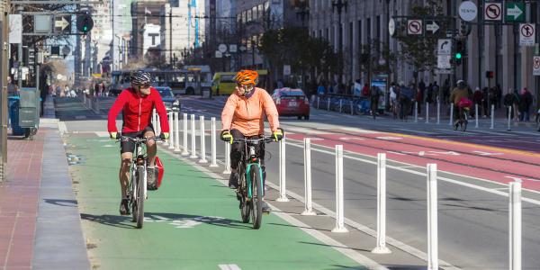Two people riding bikes on a bike lane in San Francisco. 