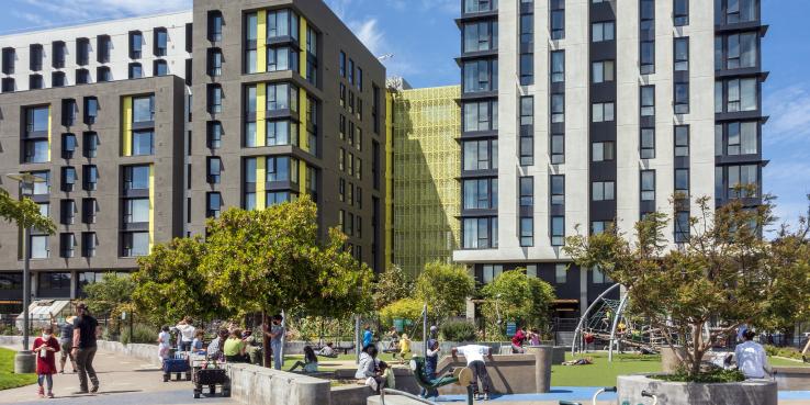 Photo of a new apartment complex with a park and playground; children and adults are enjoying the park