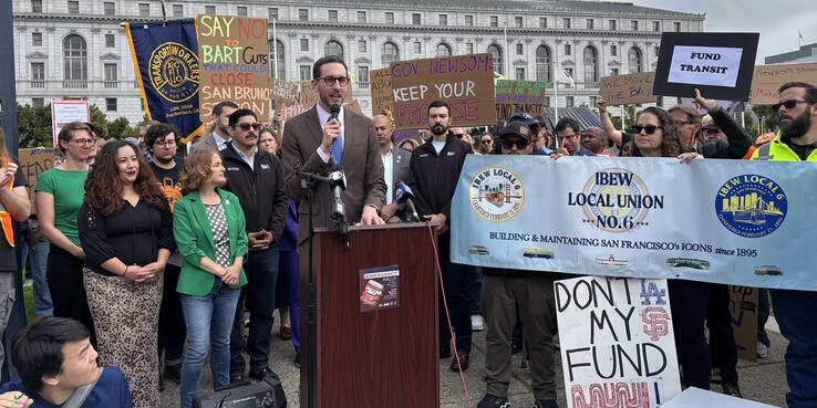 Senator Wiener at podium speaking to crowd of transit advocates