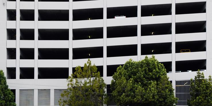 Mostly empty parking garage with trees in the front