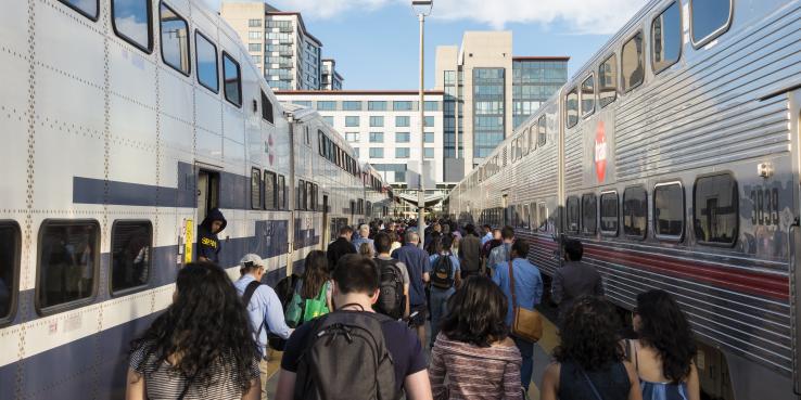 People walking in between two trains at San Francisco Caltrain station