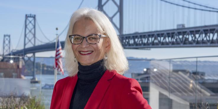 Therese McMillan standing outside in a black turtleneck, red blazer