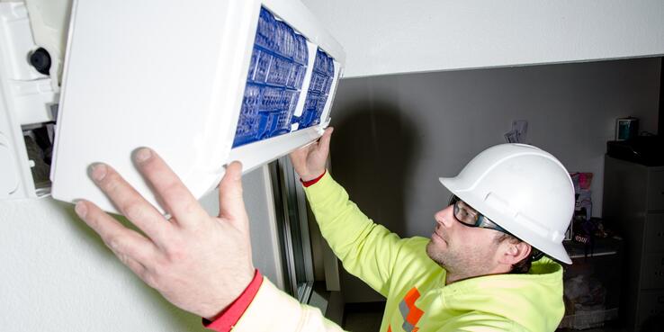 Construction worker, Jake Holmgren, installs new heating system inside resident's home in South Seattle.