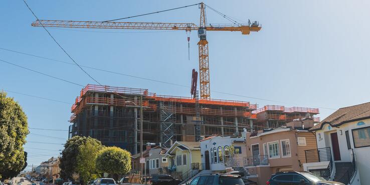 A crane at the site of a multifamily apartment building under construction in a single-family neighborhood