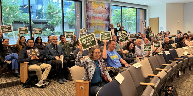 supporters of heat pump rules holding up signs 
