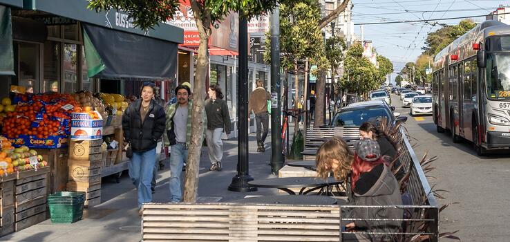photo of people walking past a produce market