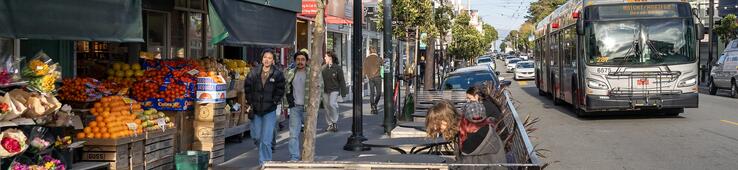 photo of people walking past a produce market