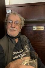 George A. Miller sitting at his booth at Sam's Grill wearing a T-shirt with one of his aphorisms