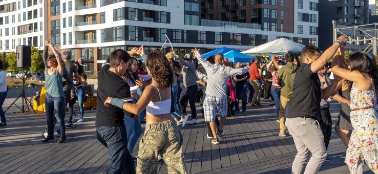 People salsa dancing outdoors in front of an apartment complex